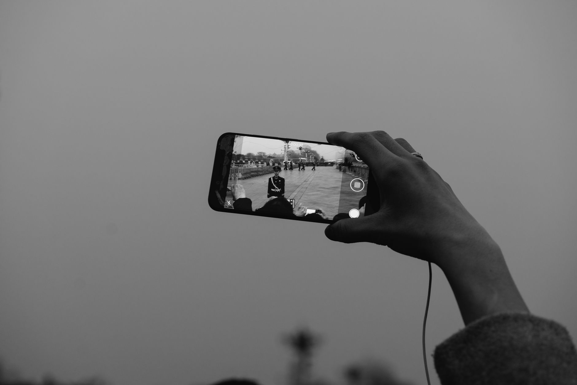 A hand holding a smartphone capturing a monochrome video at a notable Beijing location.