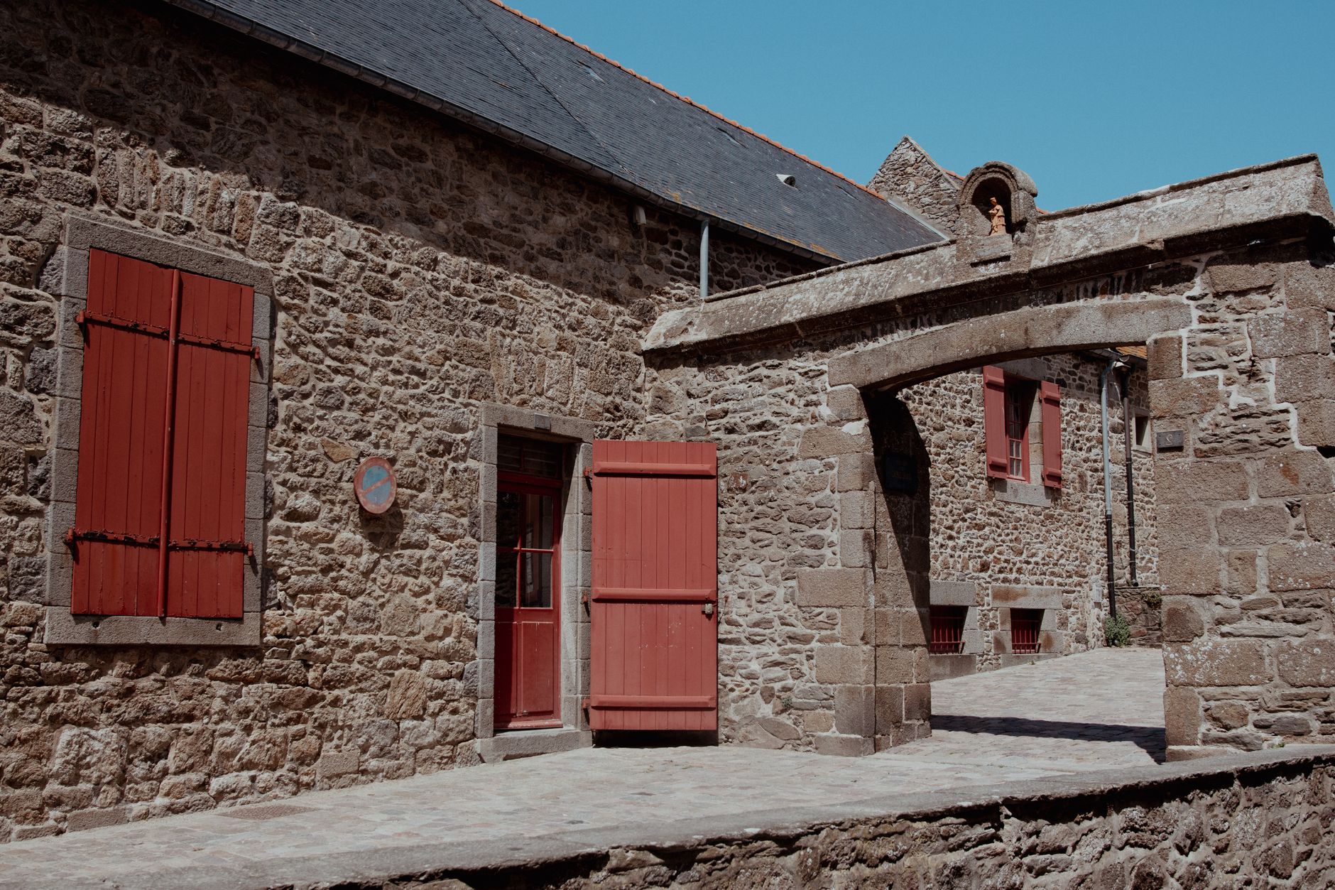 Explore charming stone buildings and rustic red shutters in picturesque Saint-Malo, France.