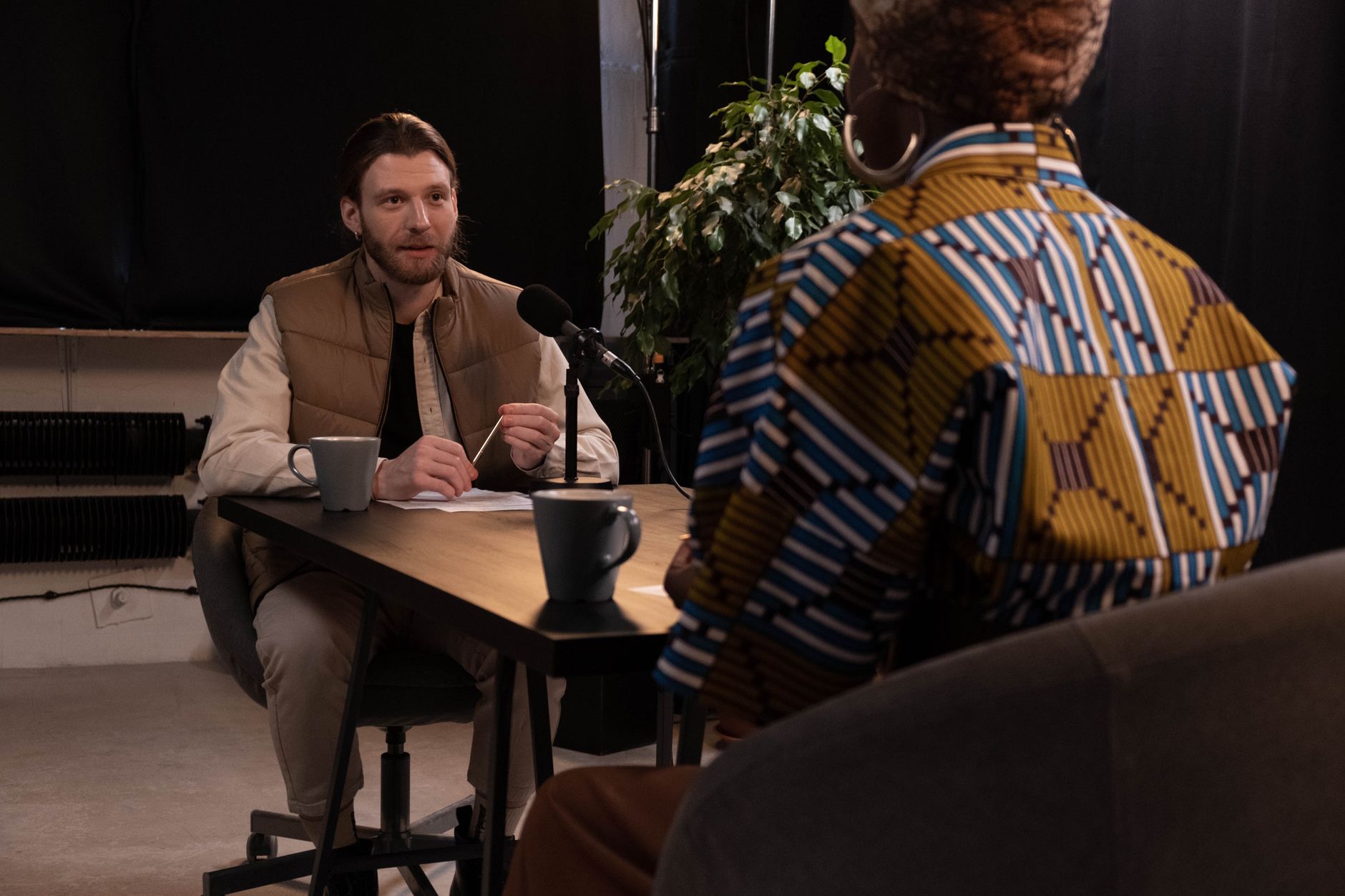A podcast interview featuring diverse hosts in a professional studio setting with microphones and coffee mugs.
