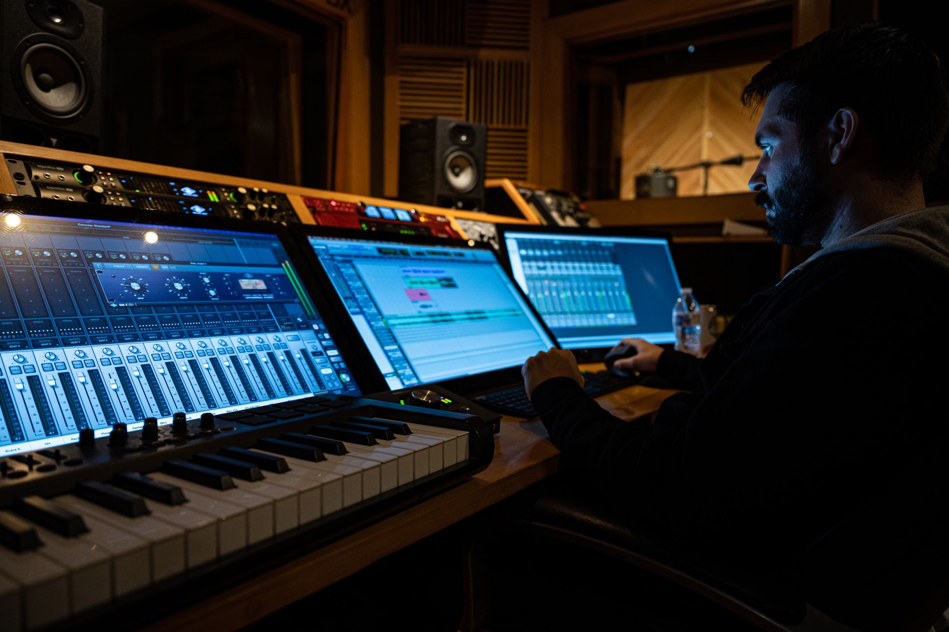Music producer working on digital audio workstation in a modern studio.